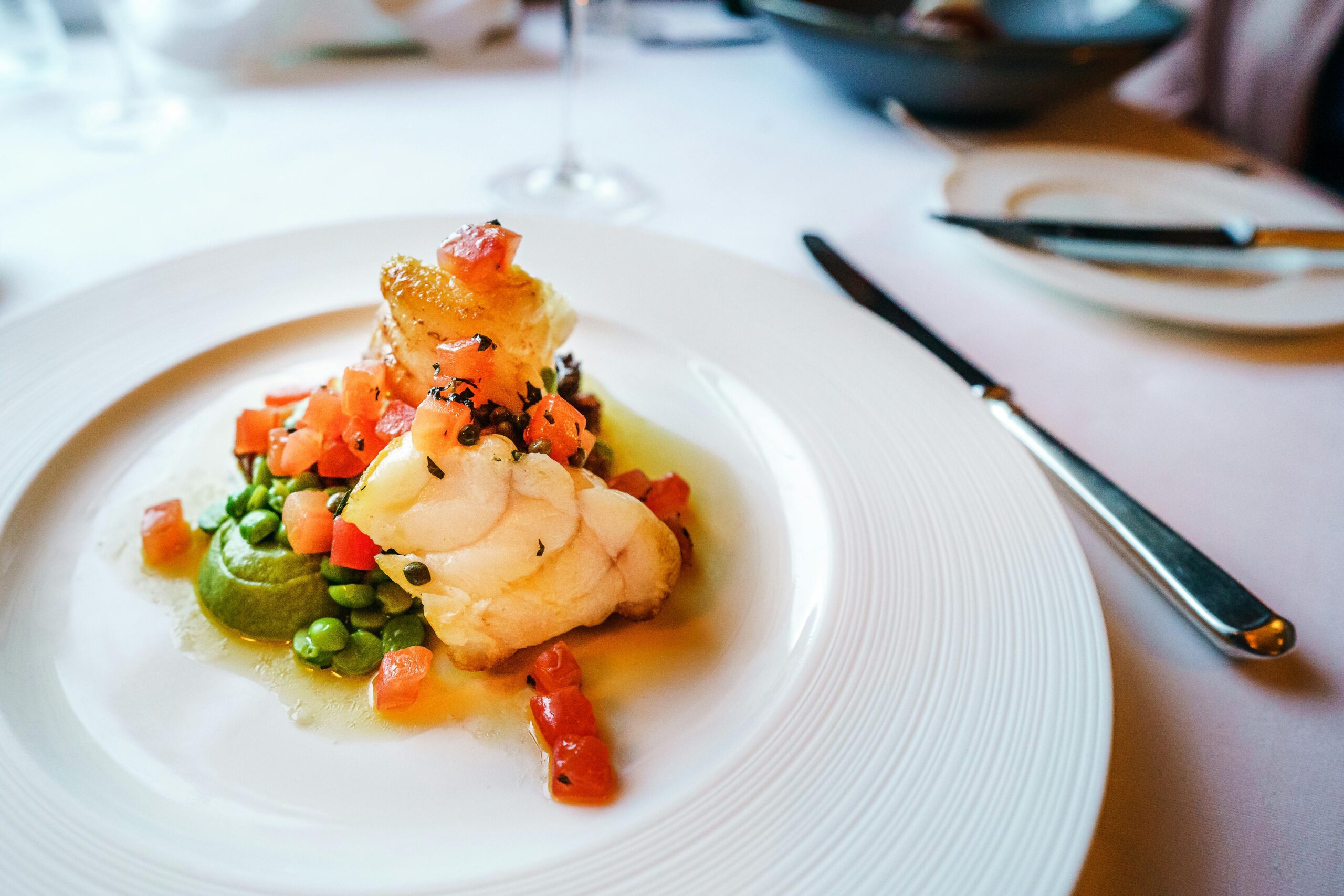 pexels photo 3611532 3611532 Elegant gourmet fish dish with peas and tomatoes, artfully plated. Perfect for cuisine enthusiasts.